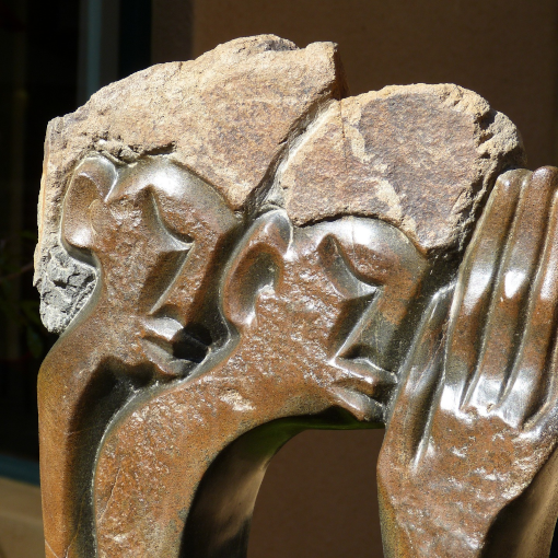 Sculpture of the heads of a couple with an hand covering their faces. Modern art.